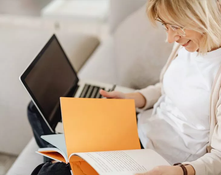 Vrouw achter laptop met boek